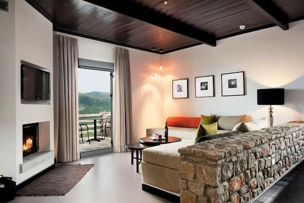 Un salon moderne doté d’une cheminée, d’un mur d’accent en pierre et d’un balcon offrant une vue agréable.