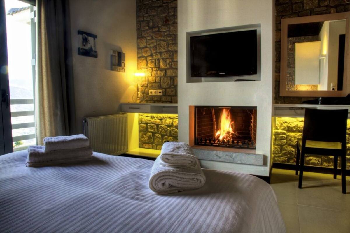 Een hotelkamer met een open haard, een bed met handdoeken, een televisie en een stenen muur.