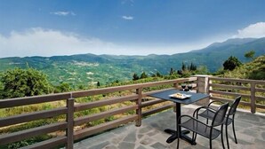 A terrace with a table and chairs overlooking a mountainous landscape.