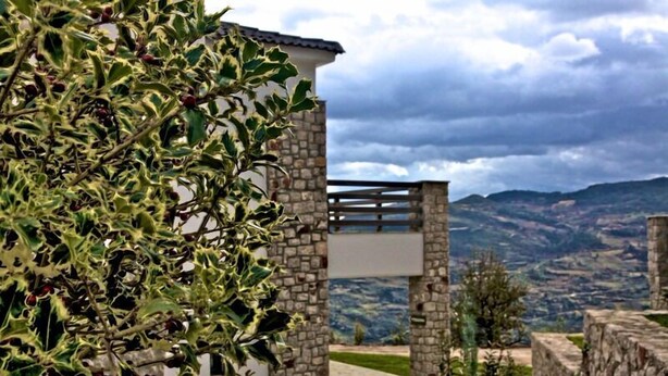 A stone building with a balcony overlooking a mountainous landscape.