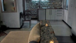 A modern interior with a stone accent wall, a sofa, and a dining area.
