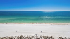 A beach with clear turquoise water, sandy shore, and a few people.