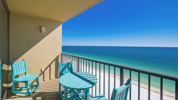 A balcony with a view of the ocean, featuring a table and two chairs.