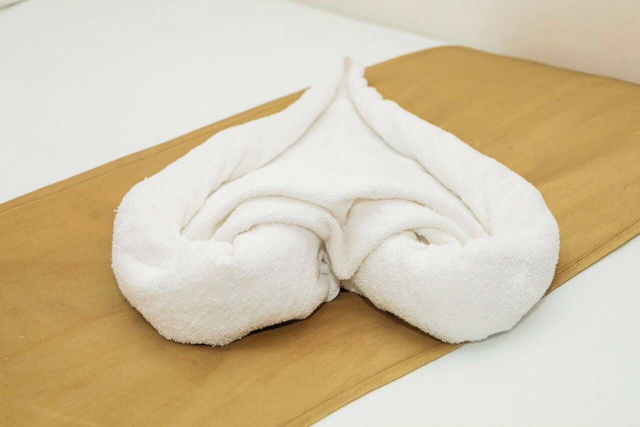 A white towel folded on a wooden surface.