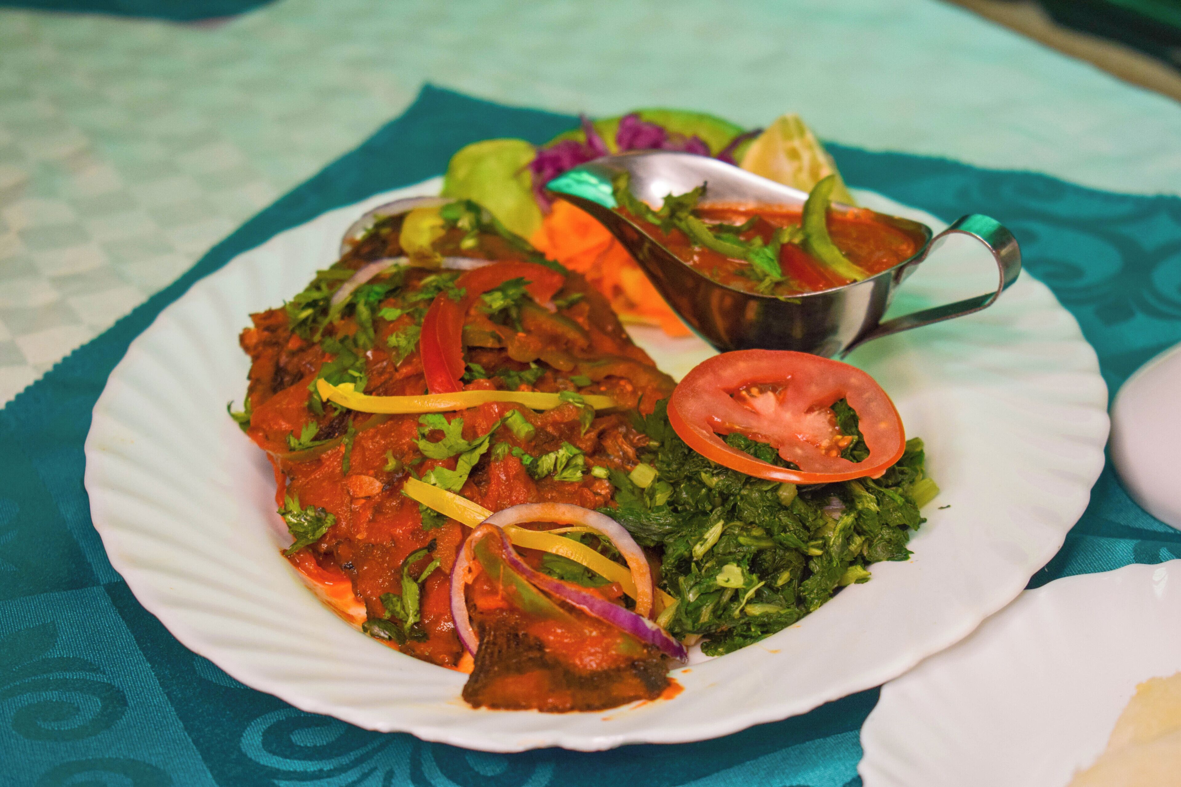 A plate of food with a variety of vegetables and a metal cup.