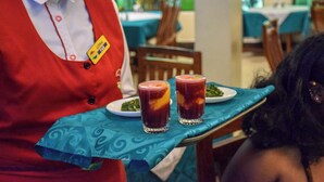 A person in a red uniform serving drinks on a tray. - Comfy Inn Eldoret (Eldoret)
