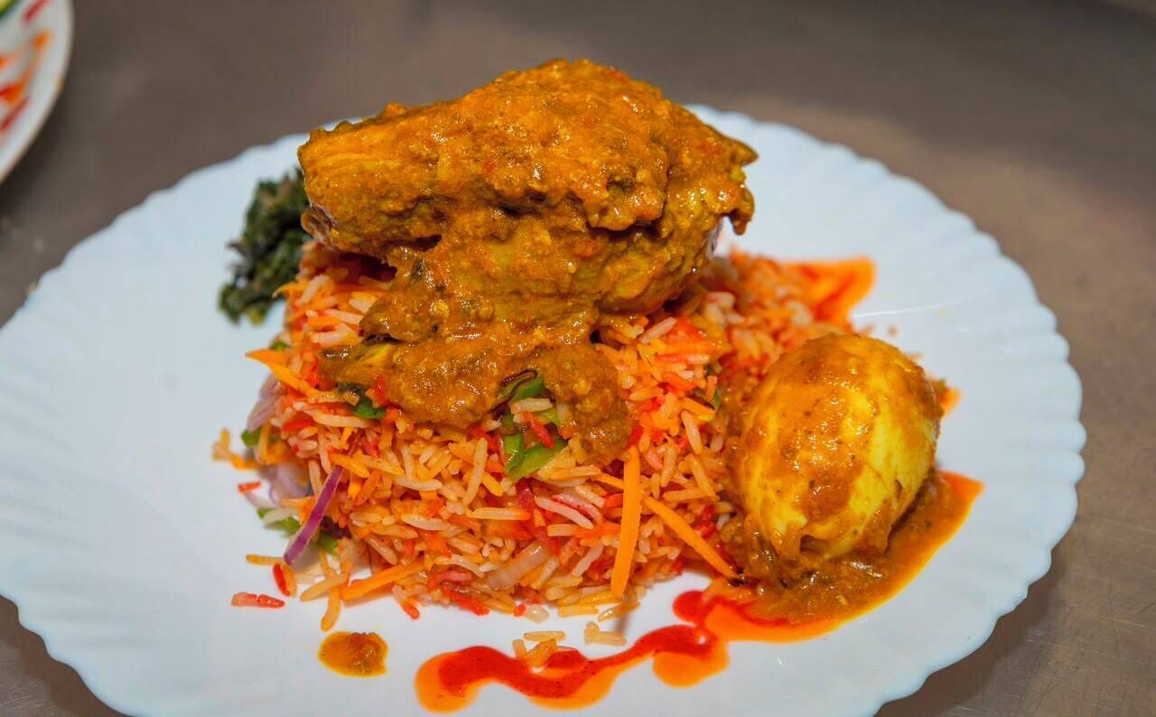 A plate of food with a chicken leg and a piece of meat, possibly fish, served with a side of rice and vegetables.