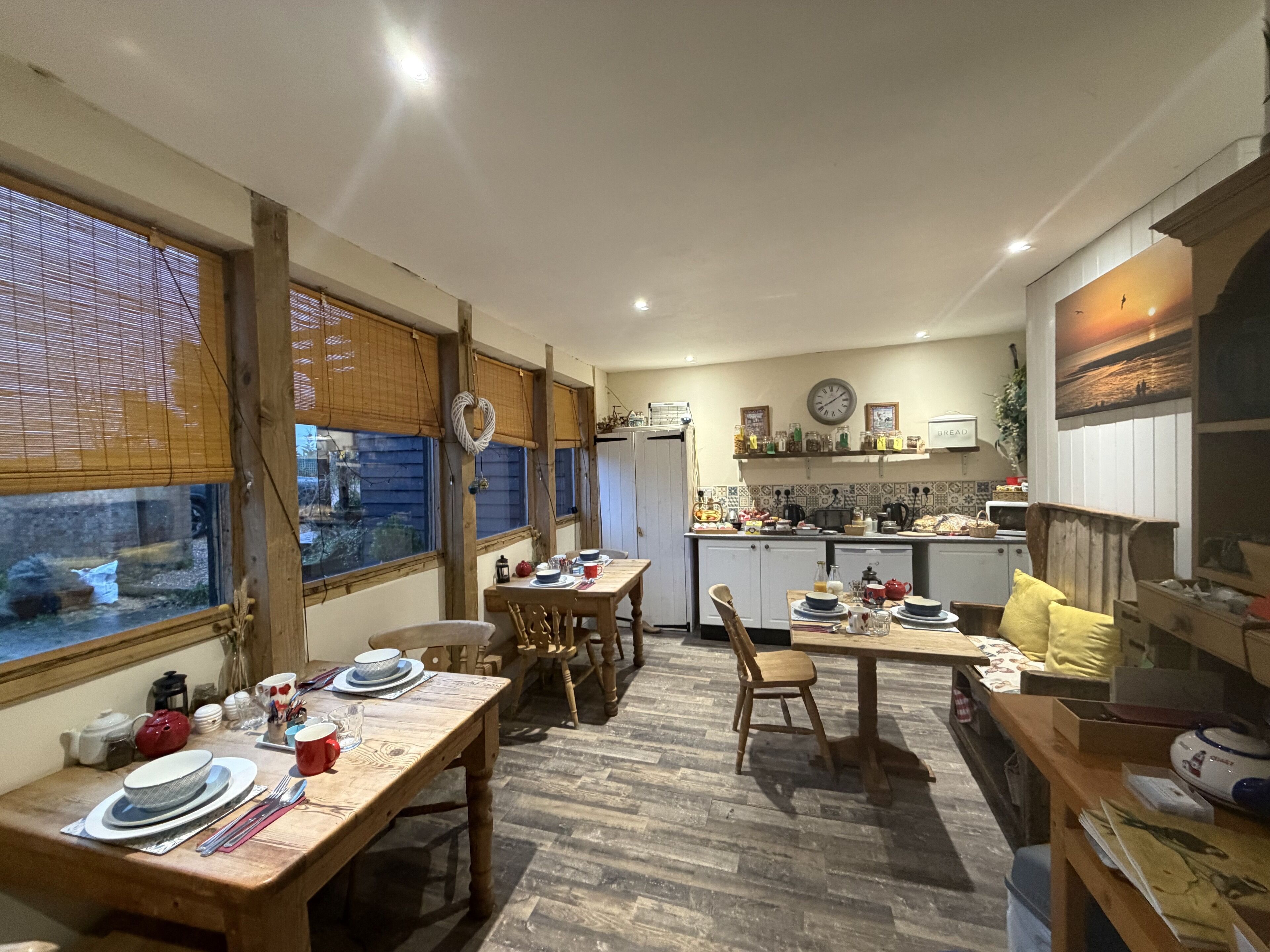 A cozy kitchen with wooden furniture, a dining table set for two, and a view through the window.