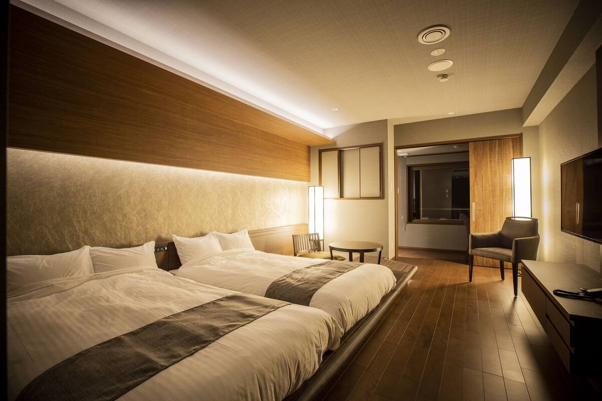 Una habitación de hotel con una cama grande, un escritorio, una silla y un televisor.