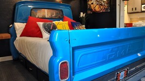 A blue vintage truck converted into a bed with a white mattress, red and yellow pillows, and a Route 66 license plate. - Close to National Parks.The Star Garage, Sleep in a Vintage Truck Bed, Cool! (Kanab)