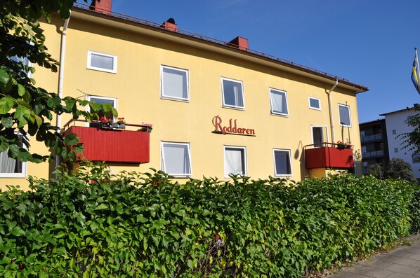 A yellow building with the name "Roddaren" on the facade, multiple windows, and a red balcony. - Roddaren Vandrarhem - Hostel (Stromstad)