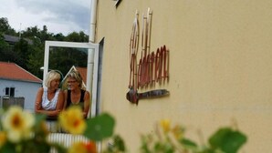 Two people sitting outside a building with a sign that reads "FARMERS".