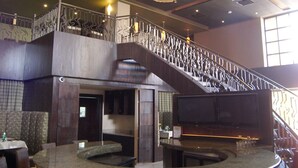 Un restaurant doté d’un bar central, de plusieurs espaces pour s’asseoir et d’un escalier menant à un niveau supérieur.