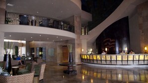 Un hall d’entrée spacieux avec un haut plafond, un comptoir d’accueil et des espaces aménagés pour s’asseoir.