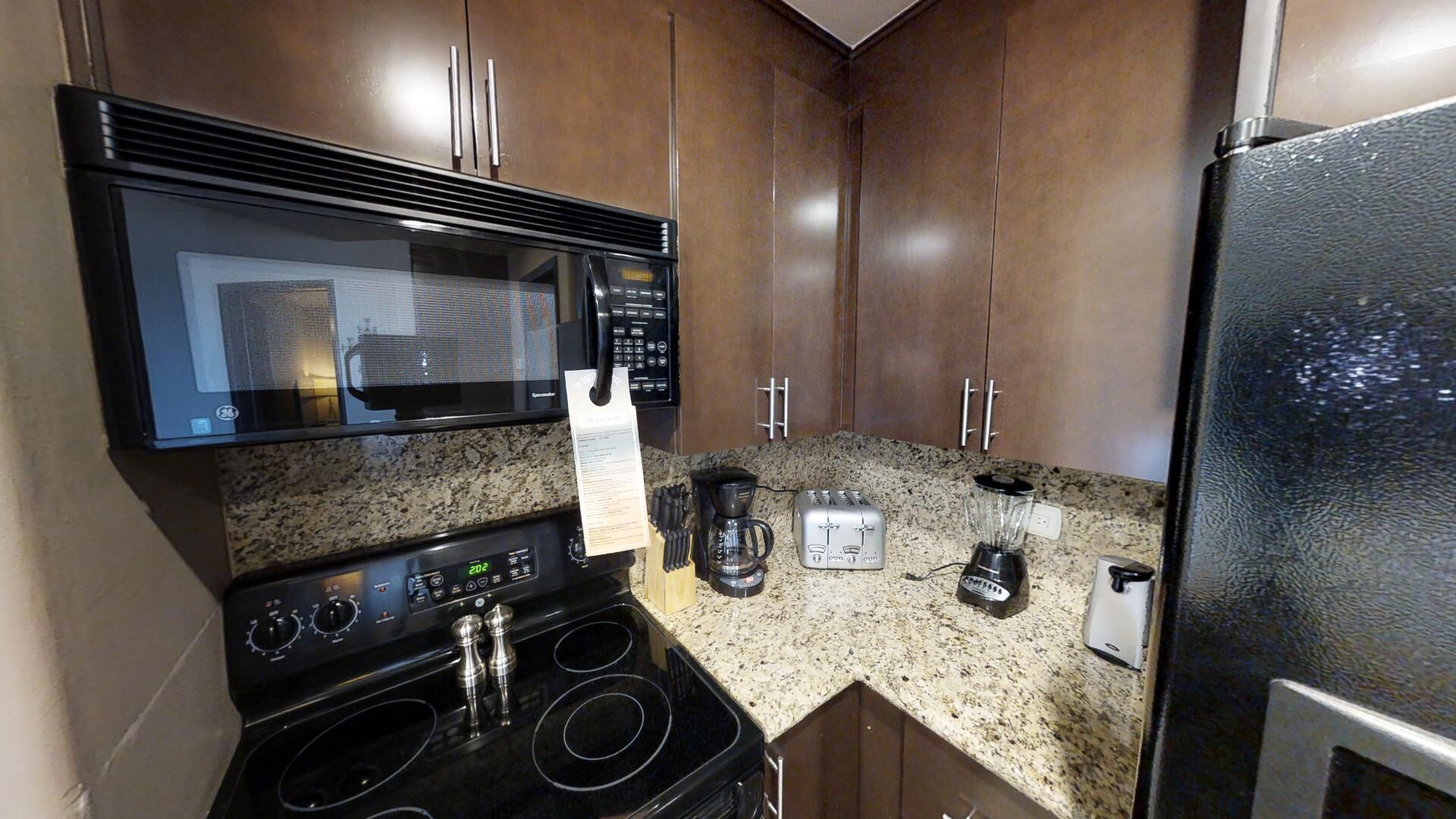 A compact kitchen with a microwave, stove, toaster, coffee maker, and refrigerator.