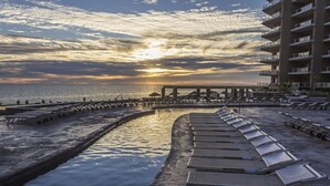 Une promenade en bord de mer, avec des chaises longues et une jetée qui s’avance dans la mer.