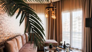 A modern living room with a brick wall, a leather sofa, a coffee table with decorative items, and a hanging light fixture.