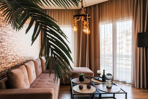 A modern living room with a brick wall, a leather sofa, a coffee table with decorative items, and a hanging light fixture.