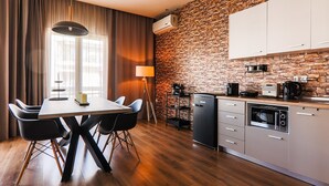 A modern kitchen with a brick wall, a dining area with a table and chairs, and a compact refrigerator.