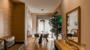 A modern dining area with a brick wall, a round table with chairs, and a large mirror.