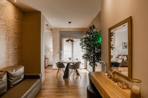 A modern dining area with a brick wall, a round table with chairs, and a large mirror.