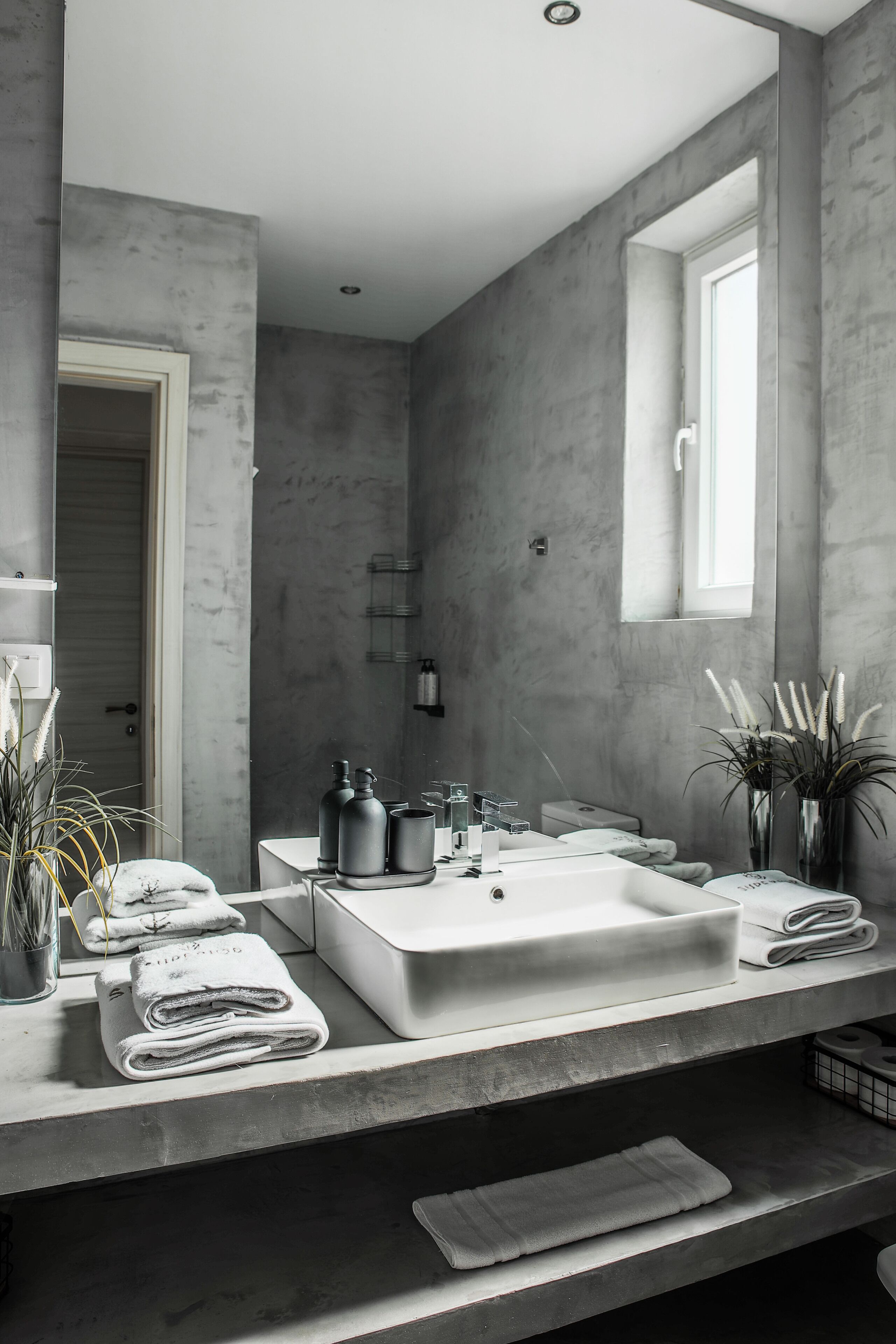 A modern bathroom with a large sink, towel racks, and a window.