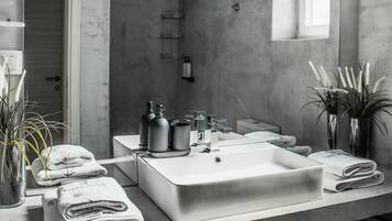 A modern bathroom with a large sink, towel racks, and a window.