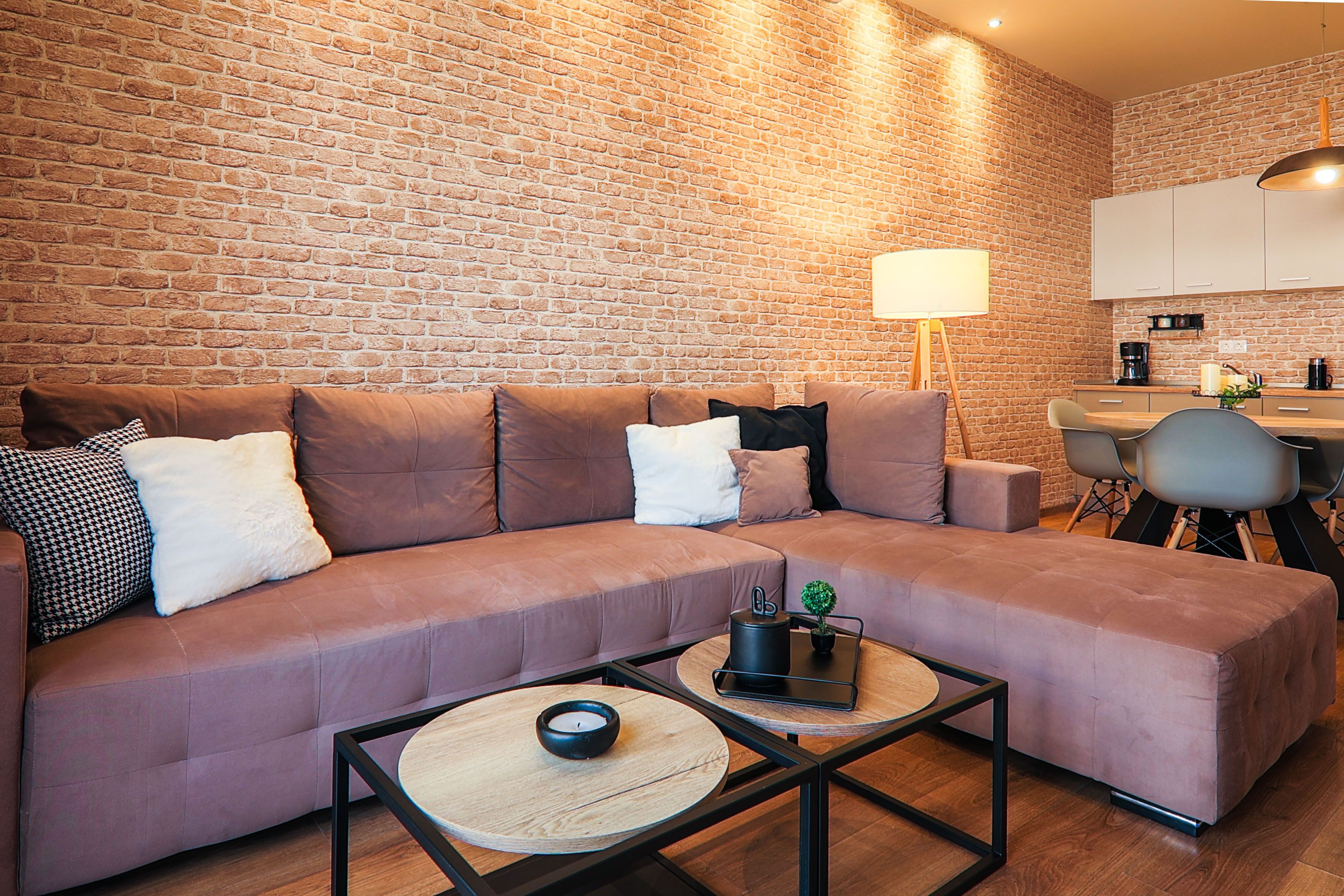 Una sala de estar moderna con un sofá modular, una mesa de centro y una pared de ladrillo.