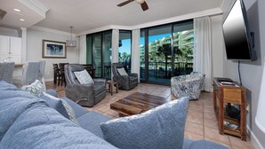 A modern living room with a grey sofa, two armchairs, a coffee table, and a TV on a wooden stand.