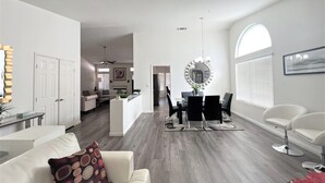 A spacious living room with a dining area, a kitchen, and a hallway leading to bedrooms. - Spacious New Remodel  Vacation Home (Las Vegas)
