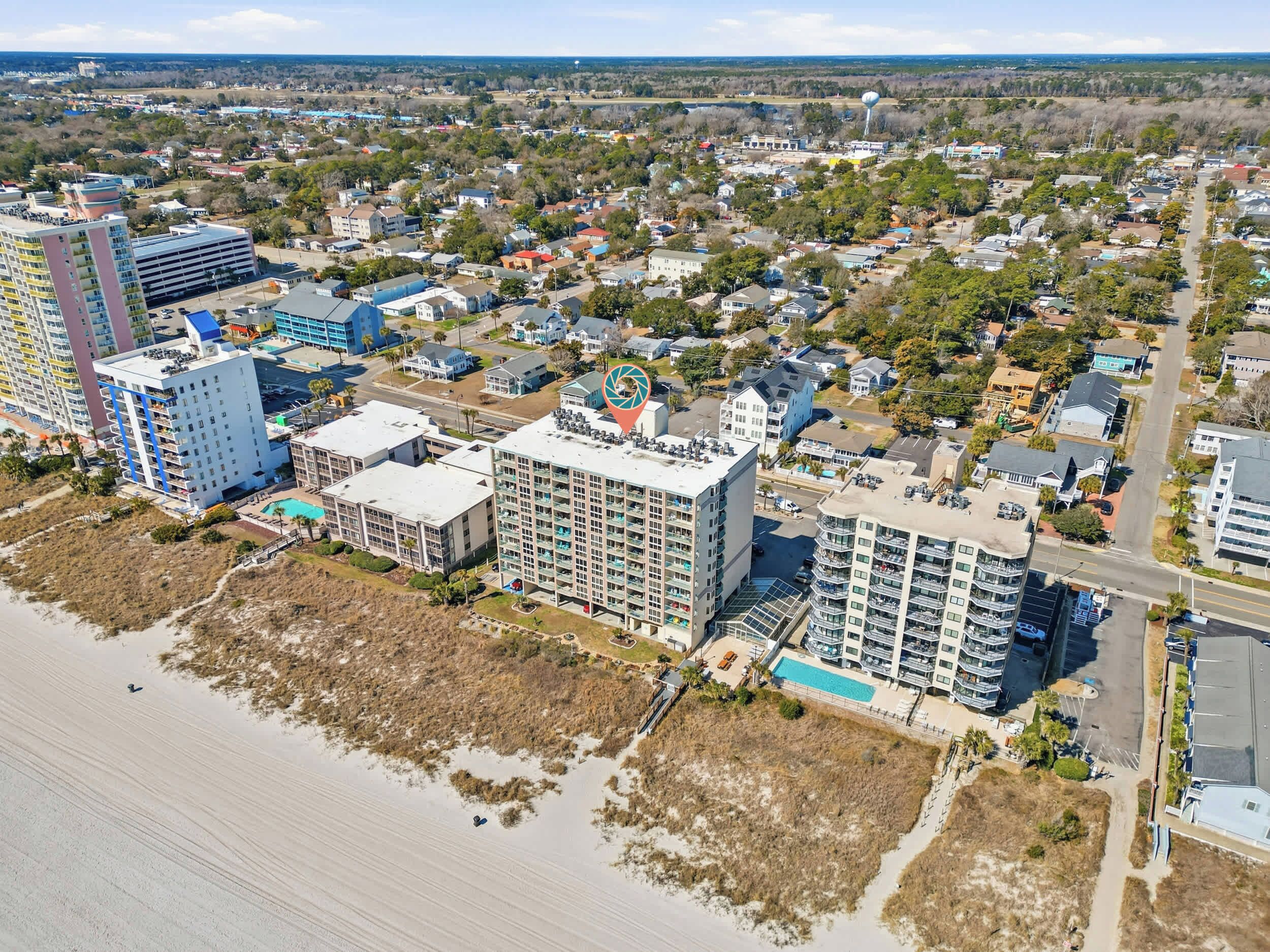 A coastal cityscape with high-rise buildings, a beach, and a golf course.