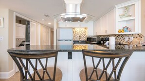 Une cuisine moderne dotée d’un îlot central, de deux tabourets de bar, d’un four à micro-ondes et d’un mur décoratif.
