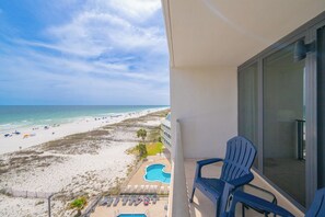 A balcony with a view of a beach and a pool.