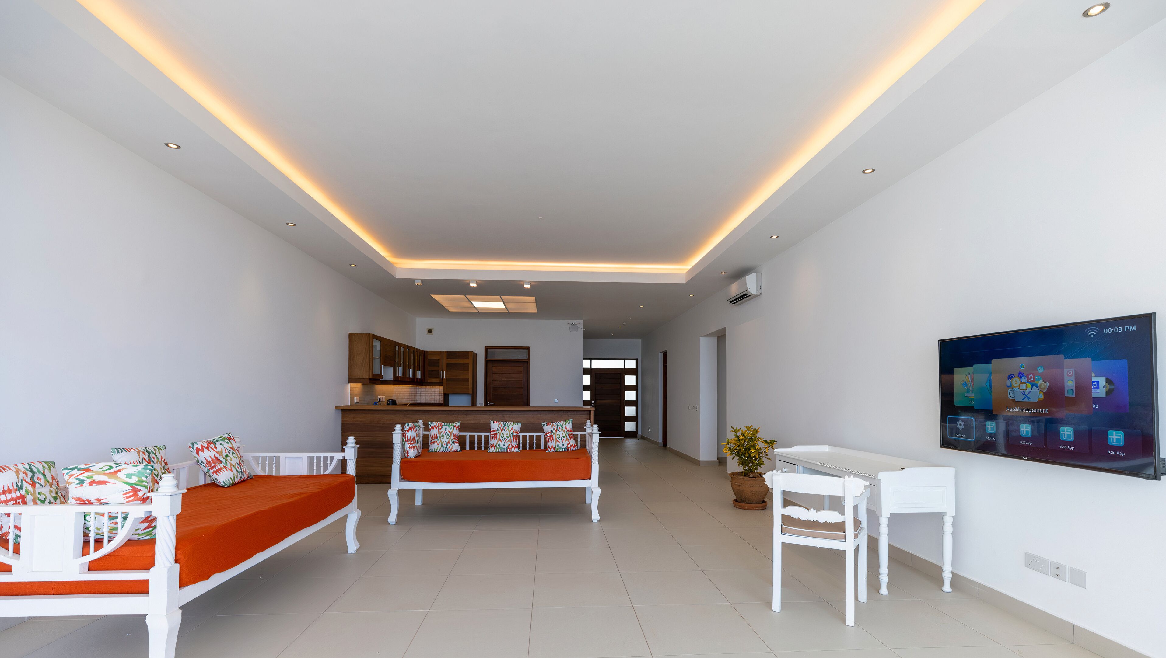 A modern living room with a sofa, a dining table, and a TV mounted on the wall.