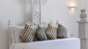 Un lit blanc avec des oreillers à rayures et une tête de lit blanche.