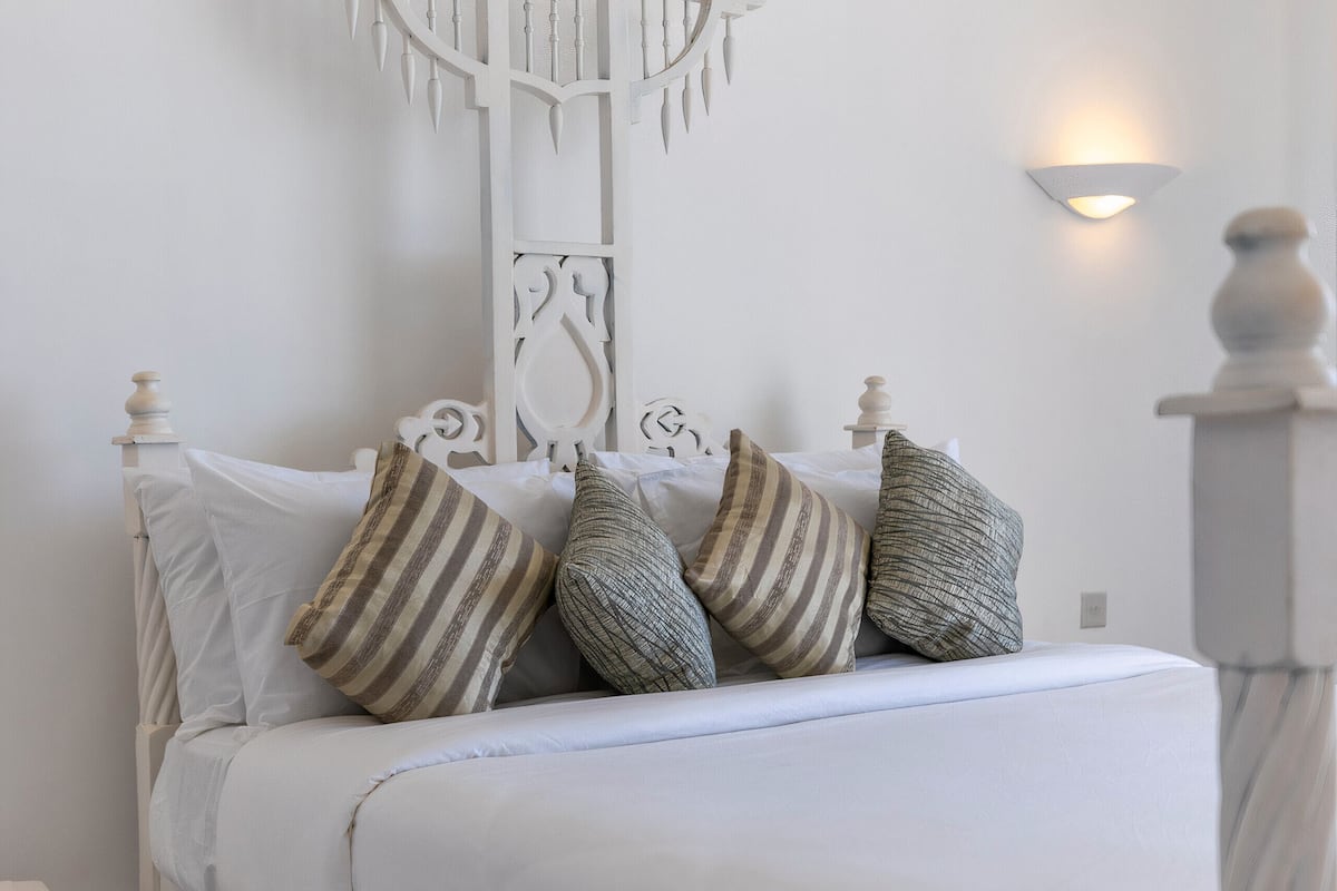 A white bed with striped pillows and a white headboard.