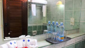 A bathroom with green tiles, a wooden door, and toiletries on the counter.
