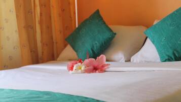 Un lit avec une literie blanche, des oreillers verts et un arrangement floral.