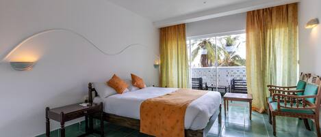 Habitación de hotel con cama, mesita de noche, silla y vistas al exterior.