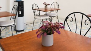 Un área de estar al aire libre con mesa de madera, sillas y adornos florales colgantes.