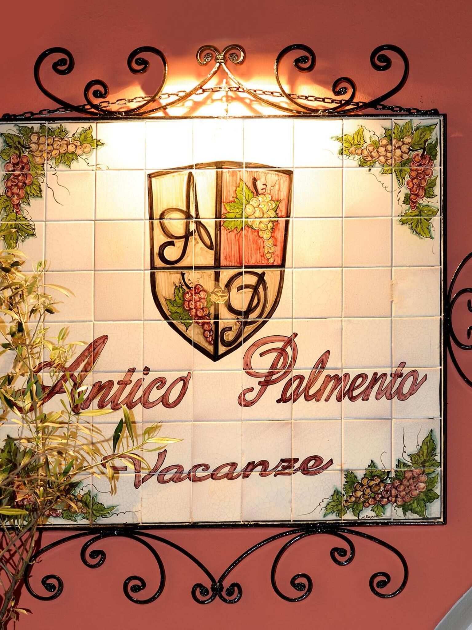 A tiled wall with a crest and the words "Antico Palazzo Vacanze".