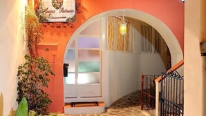 Una entrada de hotel con un patio adoquinado de piedra, un arco y un cartel con el nombre del hotel.