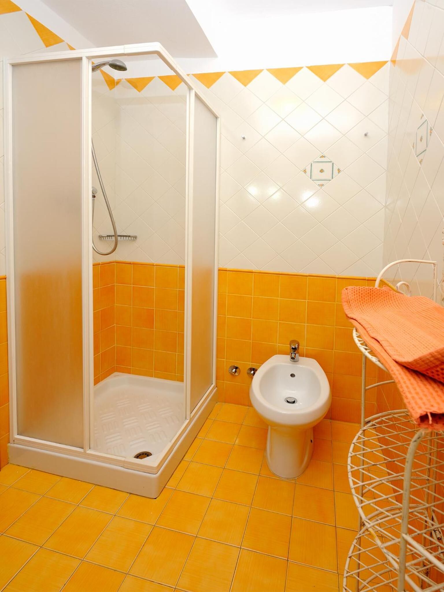 Ein Badezimmer mit Duschkabine, einem Bidet und einem Metallregal mit einem Handtuch.