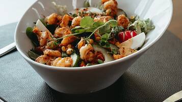 A bowl of food on a table with a napkin and a knife.