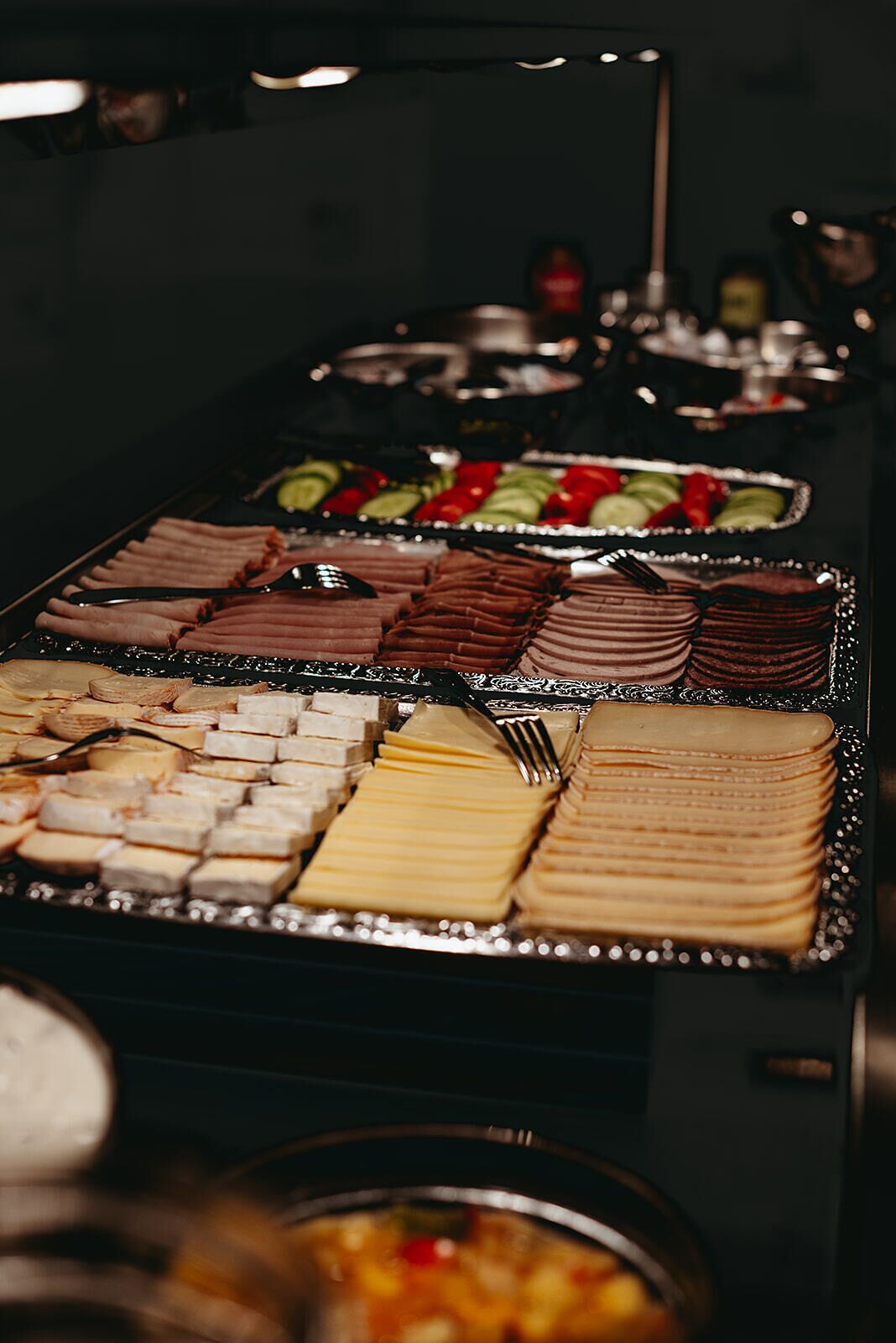 Een buffet met diverse gerechten, waaronder vleeswaren, kazen en fruit.