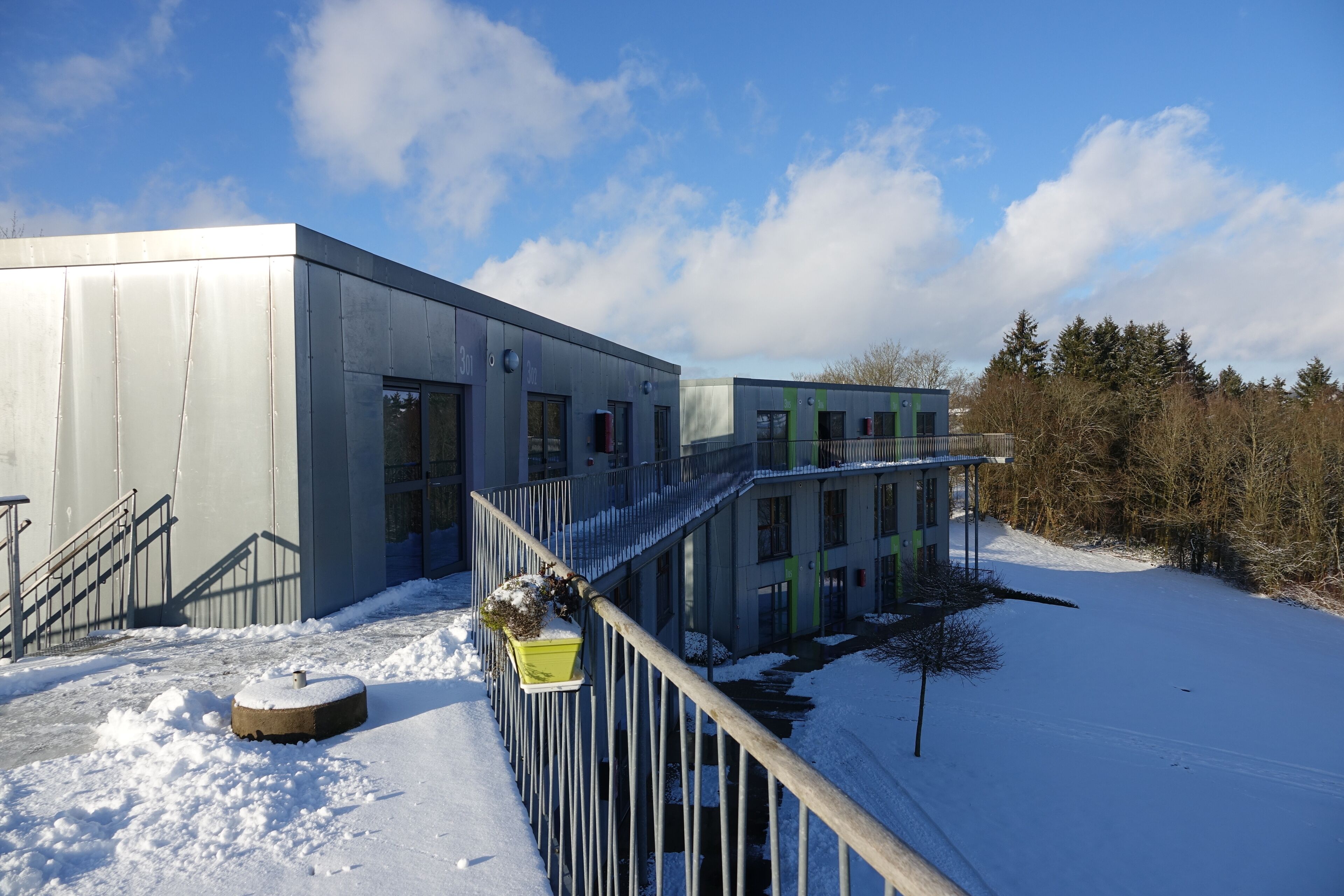 A modern building with a metal staircase and a snow-covered ground.