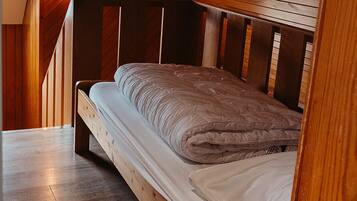 Una cama litera de madera en una habitación con techos inclinados y paredes de madera.