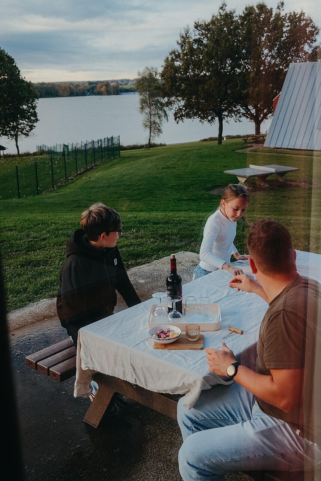 Ein Picknicktisch im Freien mit Flasche, Gläsern und Speisen.