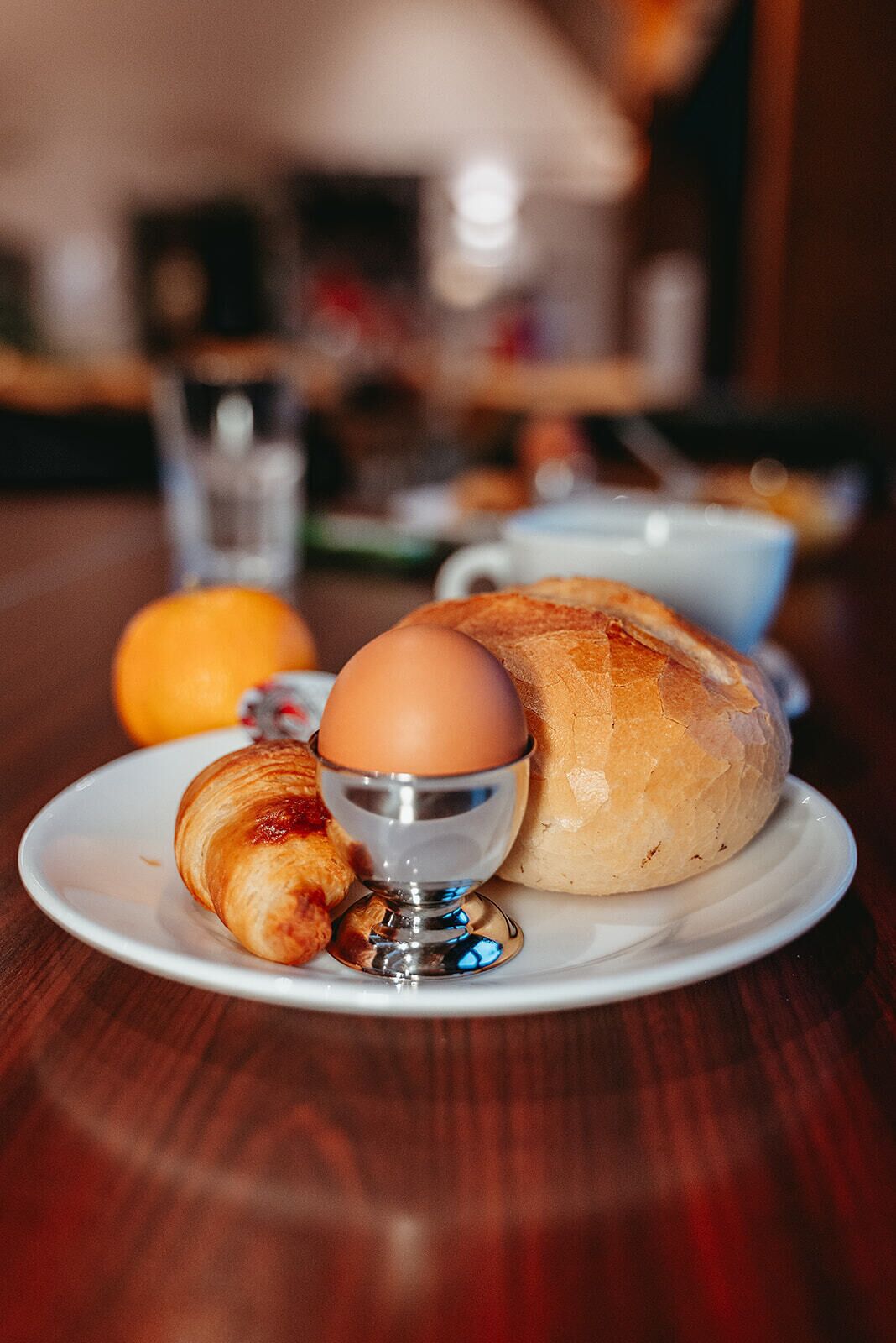 Een ontbijtje met een croissant, een gekookt ei en een brood.