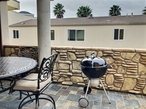 A patio with a stone wall, a table with chairs, and a barbecue grill. - Fresh look at Shore Pleasure a family fav, steps from beach and downtown (Avila Beach)